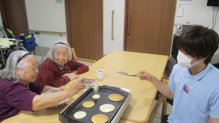 ホットケーキを焼くご利用者さまと若手スタッフ